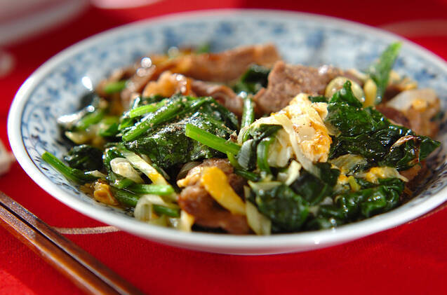 白地に青い皿に盛り付けられている牛肉とほうれん草のにんにく炒め