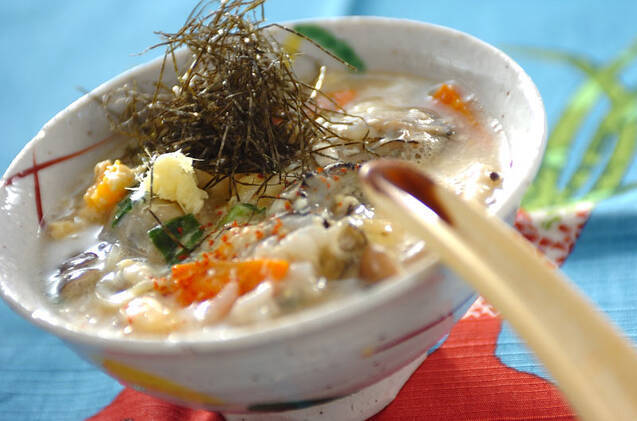 丼鉢に入っている牡蠣と野菜入りの卵雑炊、トッピングの刻み海苔
