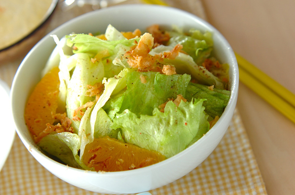 白いボウルに盛られたレタスとオレンジのサラダ