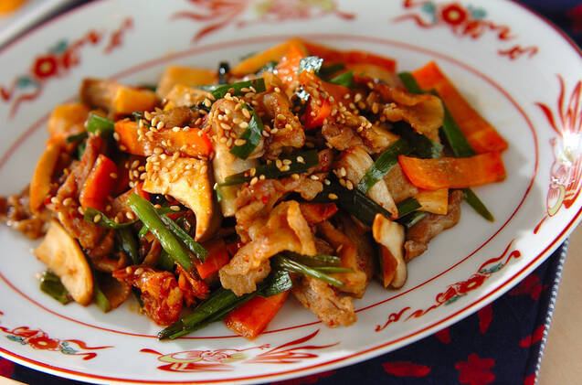 中華模様の皿に盛りつけられたキムチと豚バラ肉のプルコギ炒め