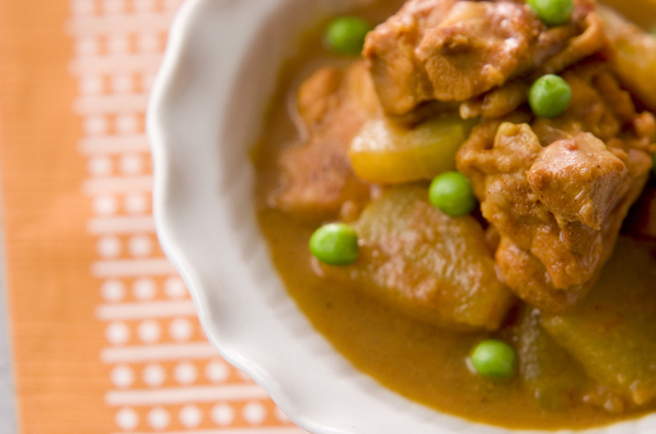 波型縁取りの皿に盛りつけられている鶏もも肉と冬瓜のカレー煮