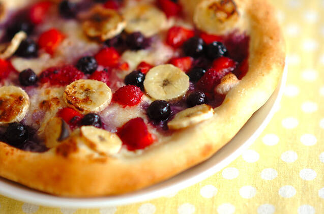 白いお皿に盛られたベリーとバナナのデザートピザ