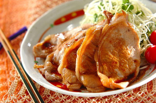 赤い模様の白いお皿にのった千切りキャベツとミニトマト、豚薄切り肉のしょうが焼き