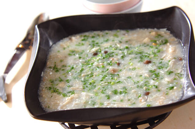 黒い角皿に盛り付けられたアサリのオートミールがゆ