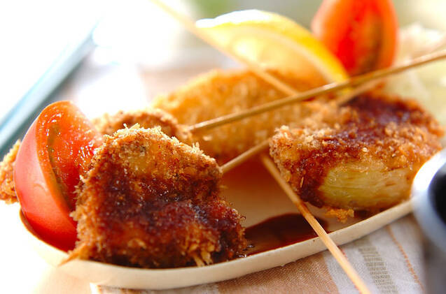 皿に盛りつけられた串カツにトマトとレモンが添えられている