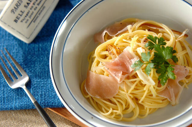 お皿に盛られたネギのマリネと生ハムのパスタ