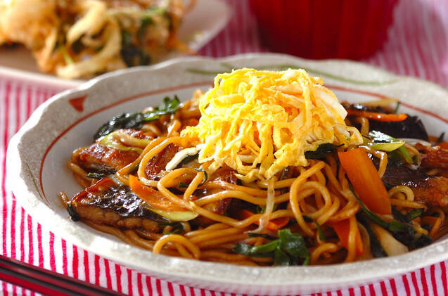 模様入りの皿に盛りつけられたうなぎ蒲焼きと錦糸卵の焼きそば