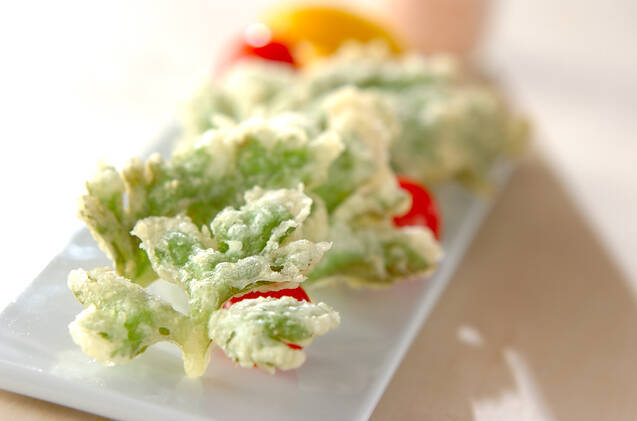 白い長皿に盛りつけられている、セロリの葉の天ぷらとミニトマト