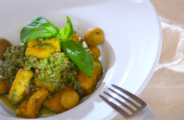 緑色のバジルソースが絡んだ黄色のかぼちゃのニョッキ