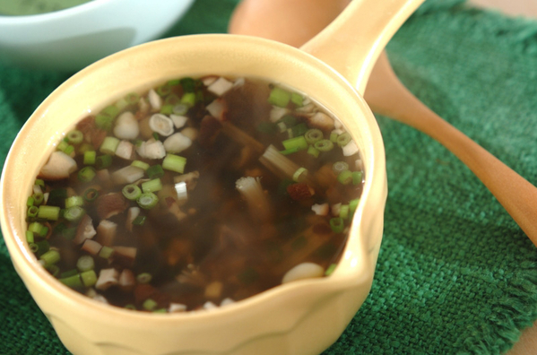 黄色いカップに入っているきのこと刻みねぎ入りのスープ