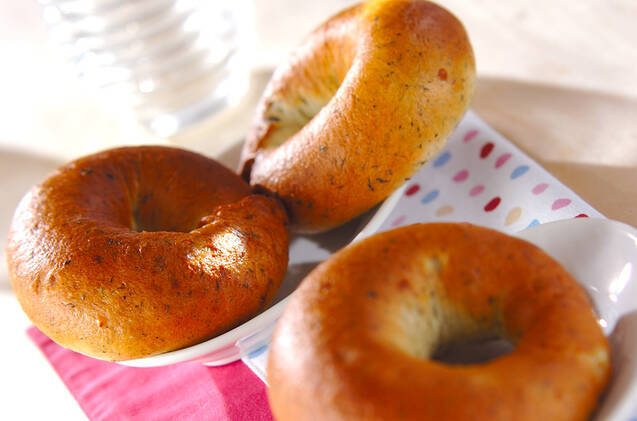 水玉のワックスペーパーの上に置かれた玉ねぎとほうれん草のベーグル