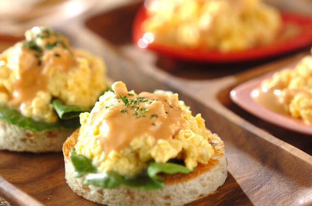木製プレートに並んだスクランブルエッグのオープンサンド