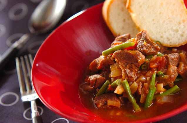 赤い皿に盛られたパンとラム肉のトマト煮込み