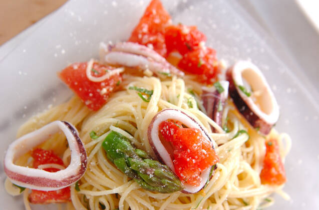 白い皿に盛りつけられたイカとトマトの冷製パスタ
