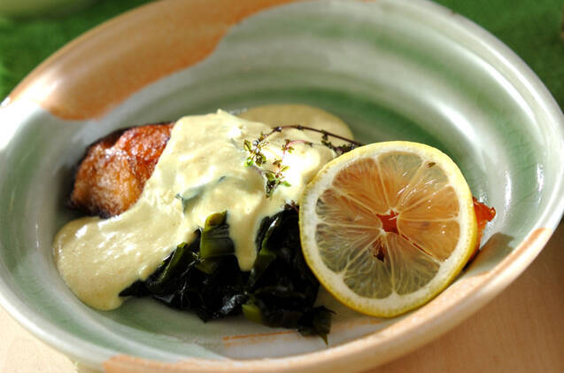 輪切りレモンとワカメが添えられたホワイトソースがけ鮭のソテー