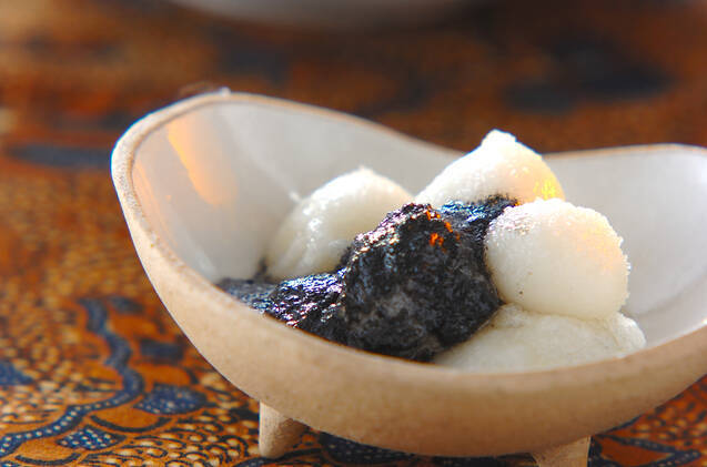 脚つきの白い楕円の小皿に盛られた揚げ白玉団子黒すりごまソース