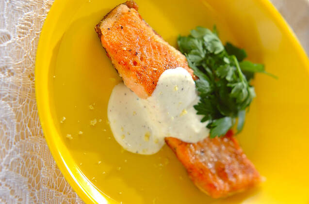黄色い皿に盛りつけられたレモンクリーム添えサーモンのムニエル
