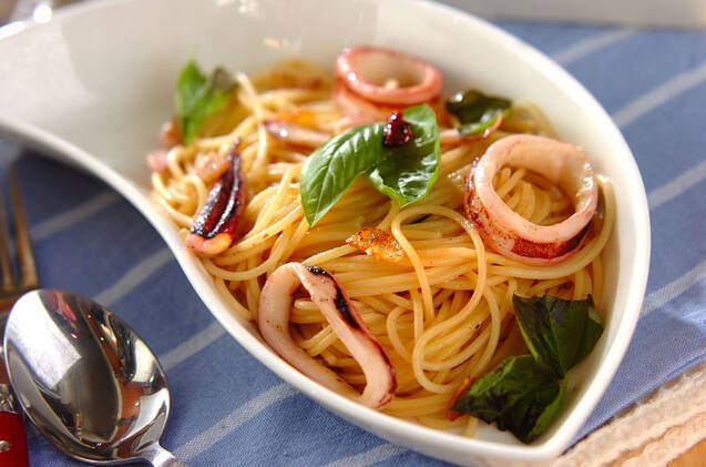 白い皿に盛りつけられたイカとバジルのガーリックパスタ