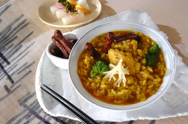 白い皿に骨付き鶏肉のおじやが盛られている様子