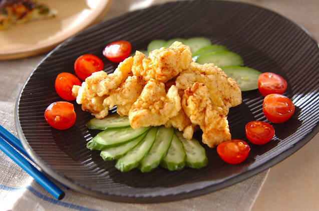 黒い皿に盛りつけられた鶏むね肉の天ぷらときゅうり、ミニトマト