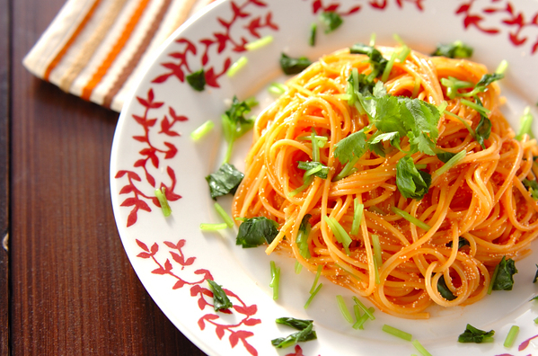 フチに赤い葉模様がある皿に盛られた、トマトジュースのたらこスパゲッティ