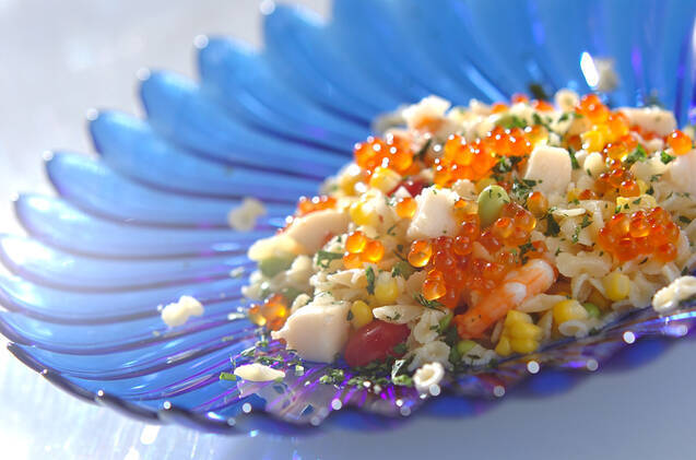 青いガラス皿に盛り付けられたファルファッリーネと帆立貝のサラダ