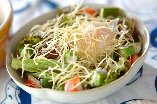 白い皿に盛り付けたサニーレタスとパリパリ麺の温玉サラダ