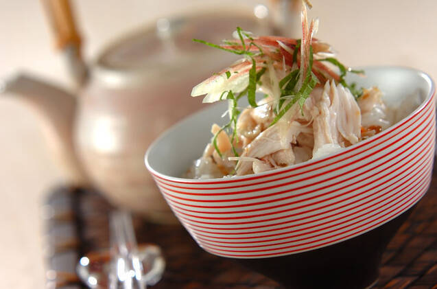 赤い模様入りの器に盛られ、みょうがと大葉をトッピングした鶏ささみの梅風味冷やし茶漬け
