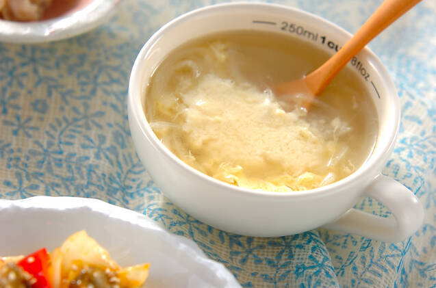 白いカップに盛りつけられた玉ねぎと粉チーズ入りの卵スープ