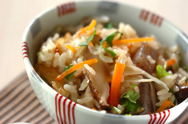 赤い模様入りのお椀に盛りつけられた野菜と油揚げのかやくご飯