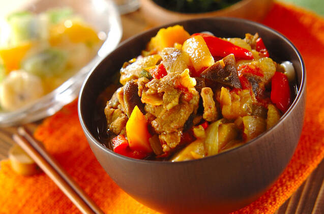 茶色の丼鉢に盛り付けられた豚肉とカラフル野菜のカレーうどん