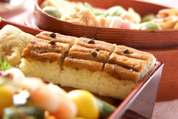 塗りの重箱に盛りつけられた煮穴子の棒寿司とそのほかの料理