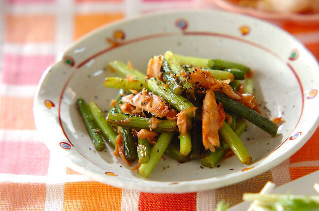 柄つきの皿に盛られたツナ缶とにんにくの芽の炒め物