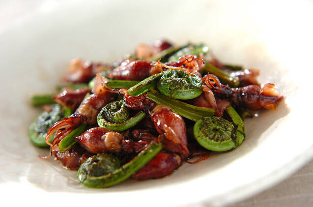 白いプレートに盛りつけられたこごみとホタルイカの炒め物