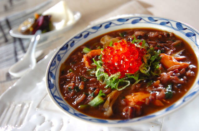 青い模様入りの丸皿に入った鮭といくらの親子黒米おじや