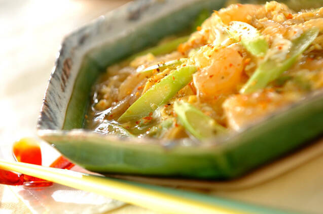 緑色の器に盛りつけられた玉ねぎとアスパラガス、むきえびの卵とじ