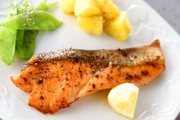 白い皿に盛られた鮭のムニエル、ゆでポテト、オランダ豆