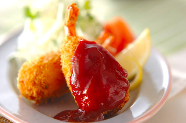 ピンクの縁取りのある白い皿に盛られた、マッシュポテトの衣で作る海老のフライ