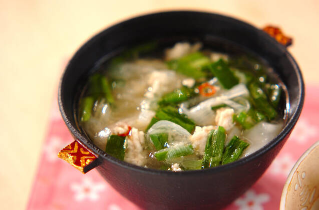 黒いお椀によそわれた鶏ひき肉やニラ、白ネギが入ったワンタンスープ