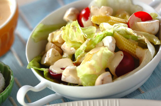 マッシュルームとレタス、ベビーコーン、ミニトマトのサラダが盛られた白い皿