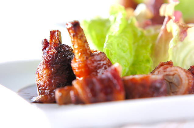 白い大皿に盛りつけられたごぼうの豚ロール焼きと葉野菜