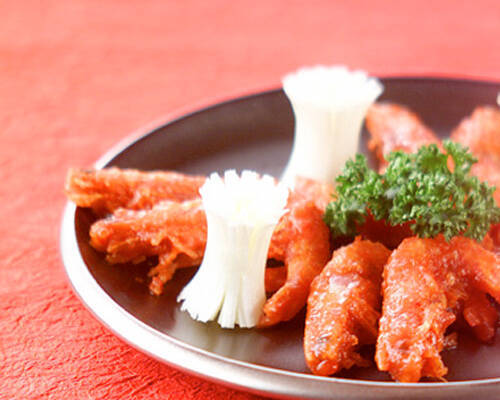 銀色の皿に盛られ、飾り切りの白ねぎとパセリを添えた車海老のピリ辛揚げ