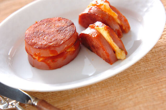 白い楕円形のお皿にソーセージのチーズはさみ焼きを盛った様子