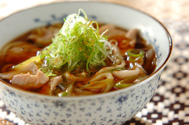 模様入りの丼鉢に盛りつけられた小ねぎが天盛りの豚肉うどん
