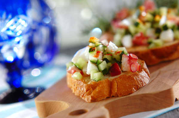 木製カッティングボードに並べられた、きゅうりとたこのブルスケッタ