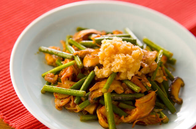 丸皿に盛り付けた豚肉とにんにくの芽の炒め物