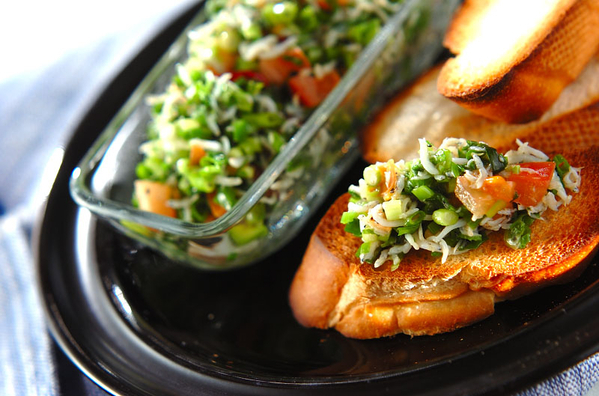 黒い皿に置かれた、しらすと青ネギのブルスケッタ