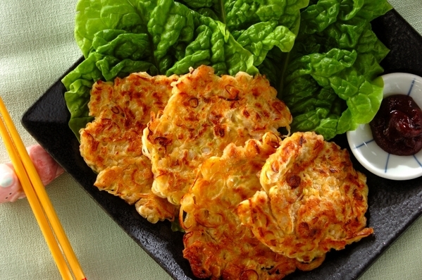 黒い皿に盛り付けられている長ねぎたっぷり豚チヂミとサンチュ