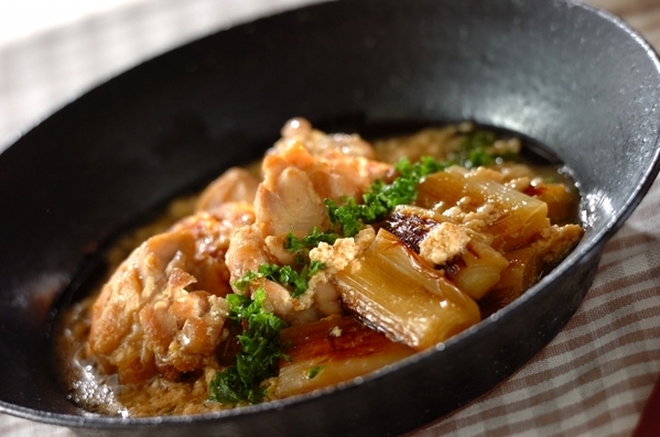 黒い皿に盛り付けられている鶏もも肉と長ねぎのクリーム煮