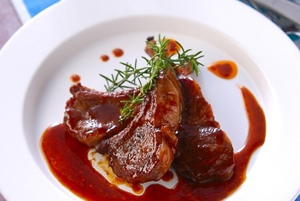 白い皿に盛り付けた骨つきラム肉のソース焼き